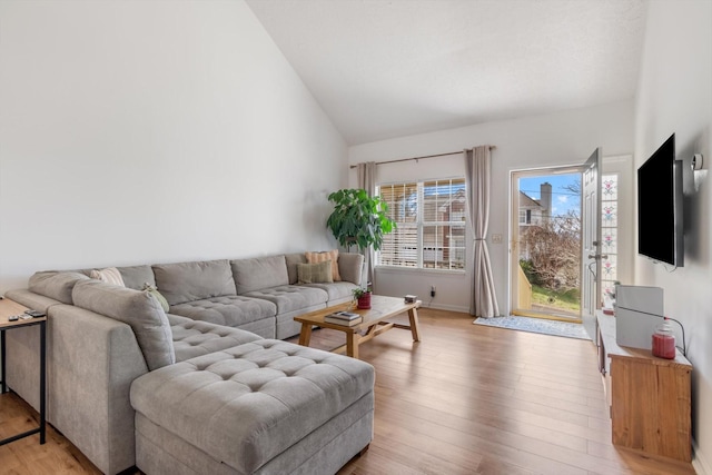 living room featuring vaulted ceiling, light wood-style flooring, and baseboards