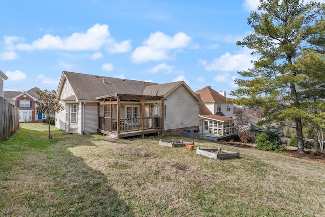 rear view of property with a garden, a lawn, a deck, and fence