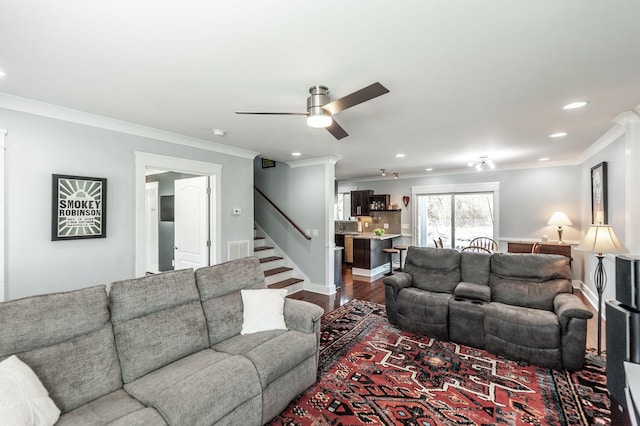 living area featuring crown molding, stairway, dark wood-type flooring, visible vents, and a ceiling fan
