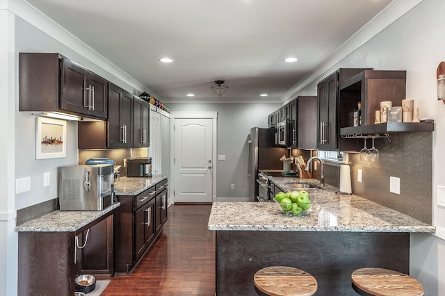 kitchen featuring dark brown cabinetry, dark wood-style floors, and light stone counters