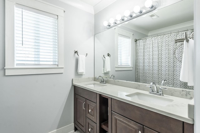 full bath featuring baseboards, double vanity, visible vents, and a sink