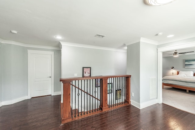 hallway with baseboards, visible vents, wood finished floors, and an upstairs landing