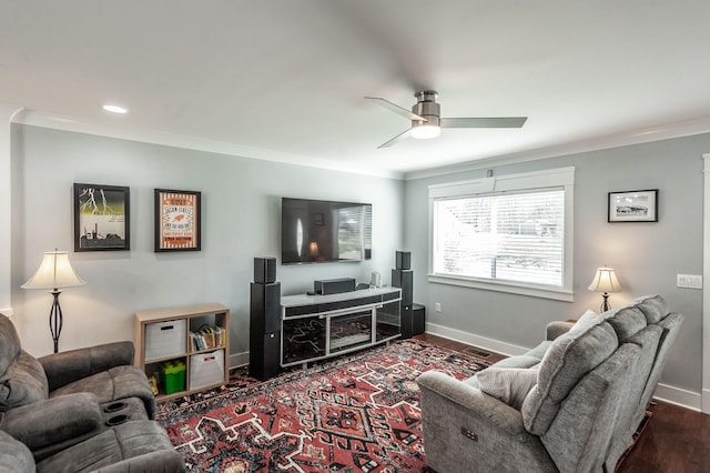 living area with dark wood finished floors, ornamental molding, baseboards, and ceiling fan