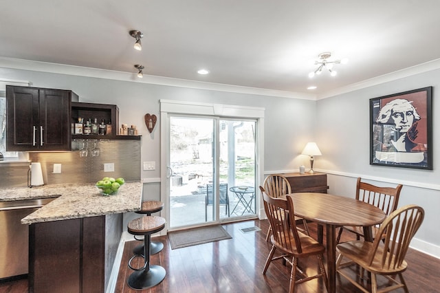 dining area featuring crown molding, baseboards, bar, dark wood finished floors, and visible vents