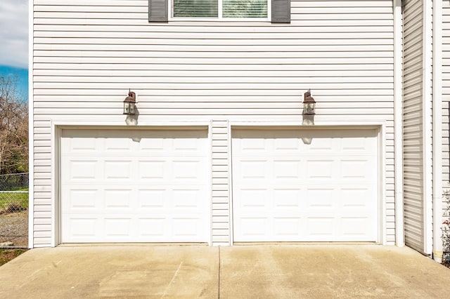 garage featuring driveway and fence