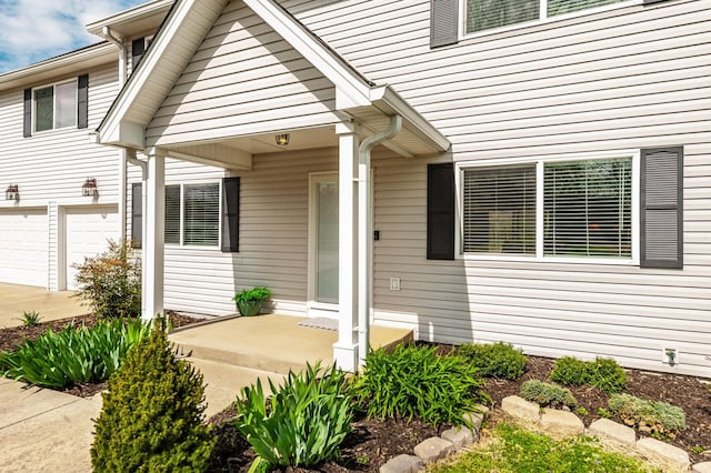 entrance to property with driveway, covered porch, and an attached garage