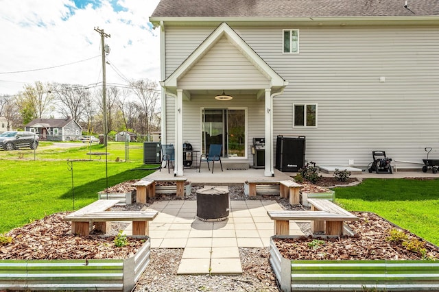 rear view of house featuring fence, a patio, an outdoor fire pit, roof with shingles, and a lawn