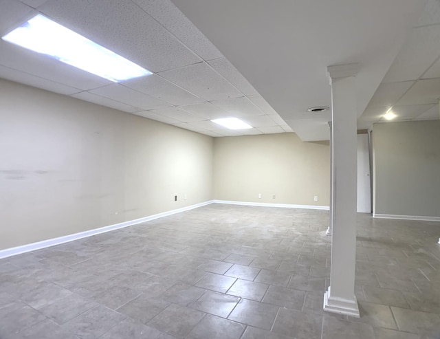 finished below grade area featuring a paneled ceiling, visible vents, and baseboards