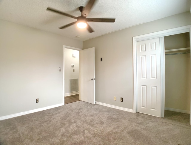 unfurnished bedroom featuring a textured ceiling, carpet flooring, visible vents, baseboards, and a closet