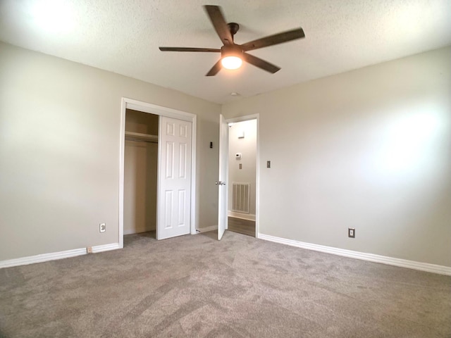 unfurnished bedroom with a textured ceiling, carpet flooring, visible vents, baseboards, and a closet