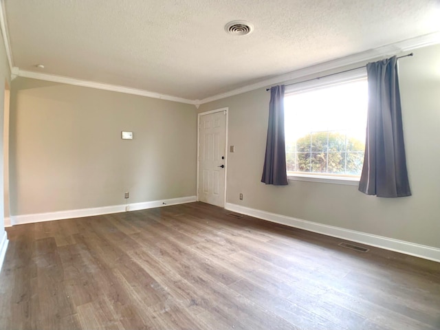 empty room with ornamental molding, visible vents, a textured ceiling, and wood finished floors