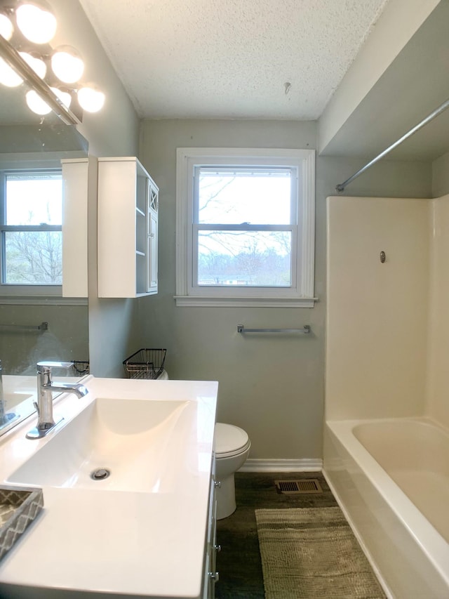 bathroom with baseboards, visible vents, toilet, a textured ceiling, and vanity