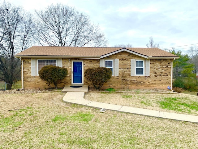 ranch-style house featuring brick siding, a front lawn, and roof with shingles