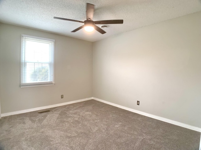 empty room featuring dark carpet, visible vents, and baseboards