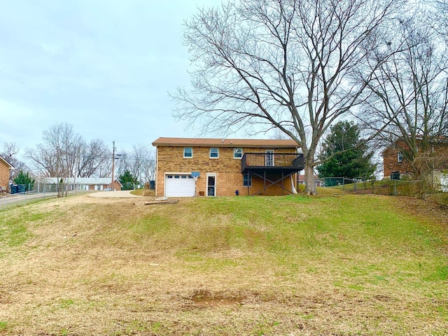 rear view of house featuring driveway, a wooden deck, a garage, and a yard