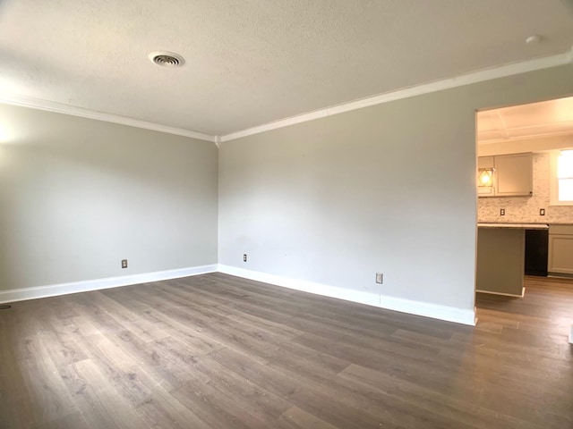 empty room with a textured ceiling, dark wood-type flooring, visible vents, baseboards, and crown molding