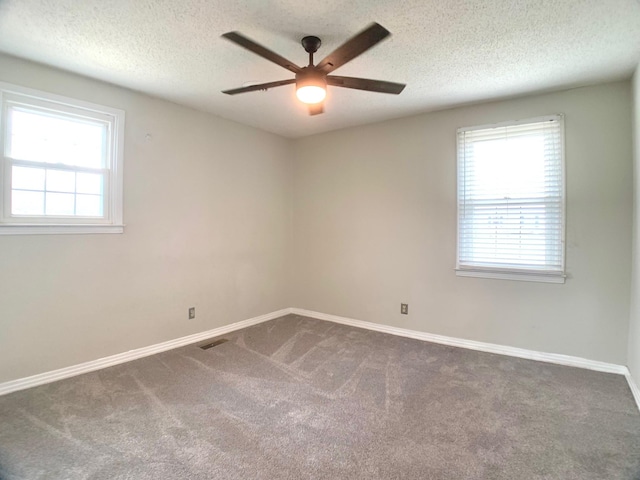 spare room with dark colored carpet, visible vents, ceiling fan, a textured ceiling, and baseboards