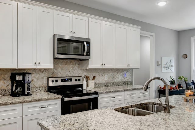 kitchen featuring appliances with stainless steel finishes, decorative backsplash, a sink, and white cabinets