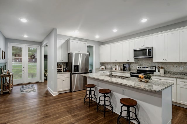 kitchen with a kitchen island with sink, appliances with stainless steel finishes, a sink, and white cabinetry