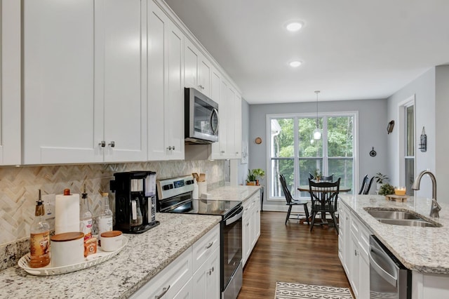 kitchen with stainless steel appliances, white cabinets, a sink, and hanging light fixtures