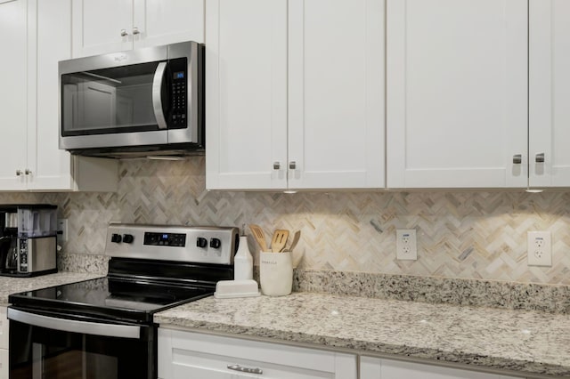 kitchen featuring appliances with stainless steel finishes, white cabinets, and light stone counters