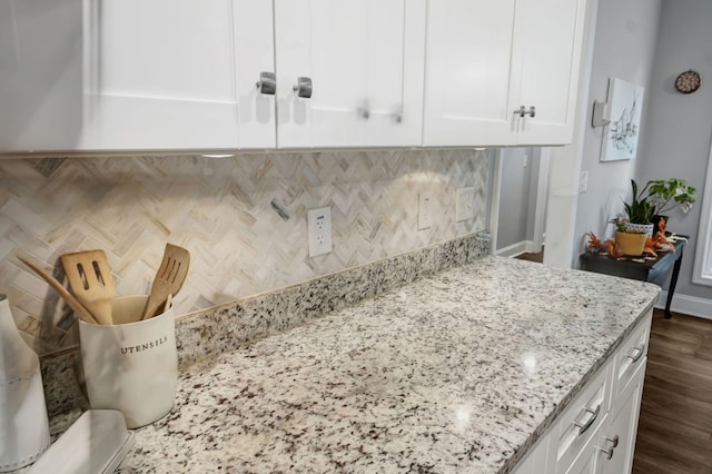 interior details featuring baseboards, white cabinetry, decorative backsplash, and light stone countertops