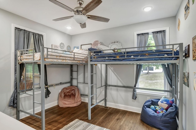 bedroom featuring multiple windows, baseboards, and wood finished floors