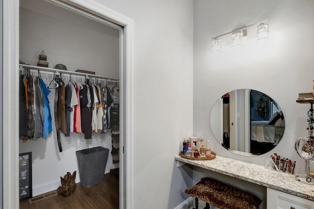 bathroom featuring a walk in closet, visible vents, baseboards, and wood finished floors