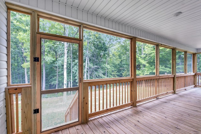 unfurnished sunroom featuring a healthy amount of sunlight and a view of trees