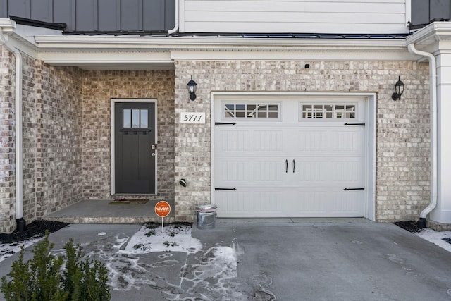 doorway to property featuring a garage, board and batten siding, and concrete driveway