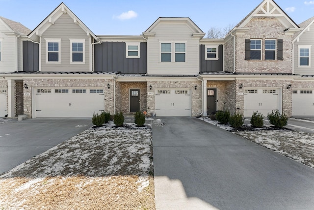 townhome / multi-family property with board and batten siding, concrete driveway, brick siding, and a standing seam roof