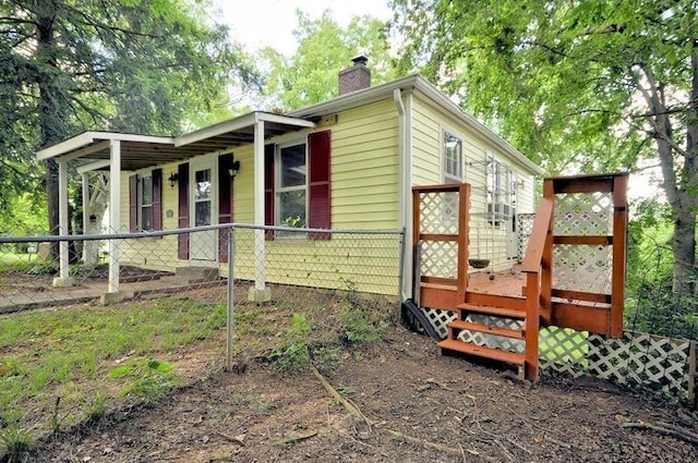 view of side of home with a fenced front yard and a chimney