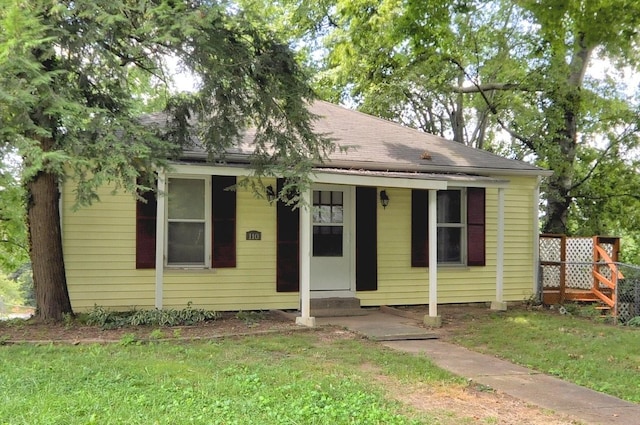 bungalow with a shingled roof, entry steps, and a front lawn