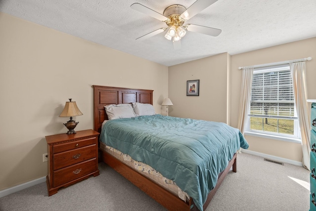 bedroom featuring light carpet, a textured ceiling, and baseboards