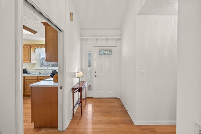 foyer entrance featuring baseboards and light wood-style floors