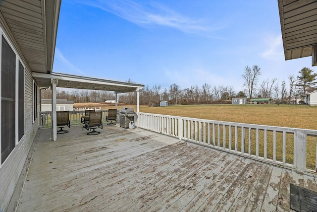 deck featuring a shed, a lawn, an outdoor structure, and a grill