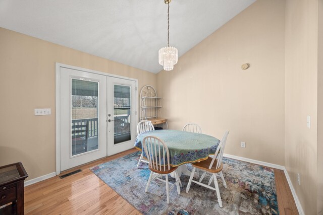 dining space featuring visible vents, baseboards, light wood-style flooring, vaulted ceiling, and french doors