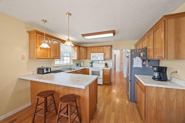 kitchen featuring white appliances, light countertops, a sink, and hanging light fixtures