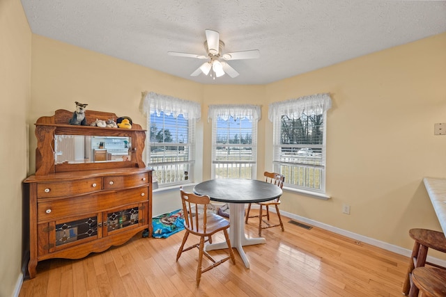 dining area featuring baseboards, light wood-style flooring, visible vents, and a ceiling fan