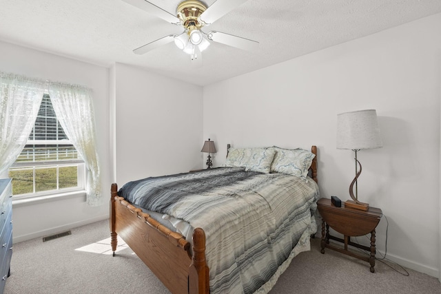 bedroom featuring light carpet, baseboards, visible vents, and a textured ceiling