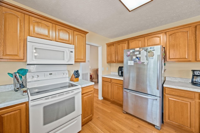 kitchen featuring white appliances, light countertops, and light wood-style floors