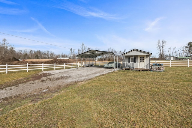 view of front of house with a detached carport, a rural view, fence, and a front lawn