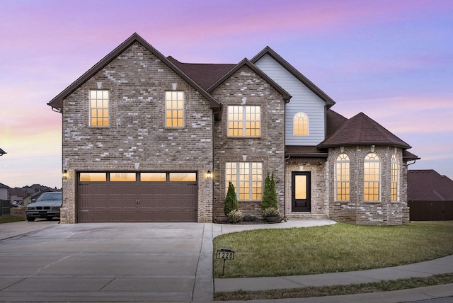 view of front of property featuring an attached garage, a yard, driveway, and brick siding