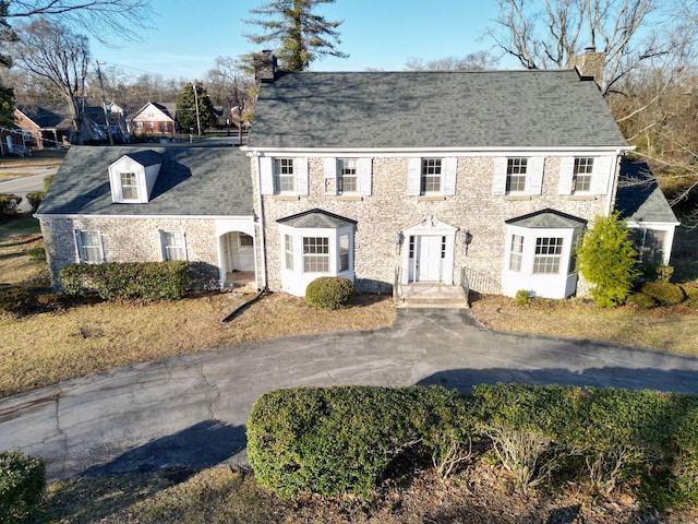 colonial inspired home featuring driveway and a chimney