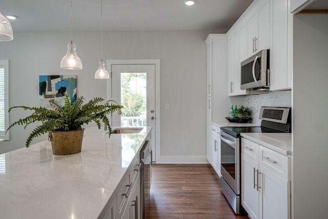 kitchen with white cabinetry, appliances with stainless steel finishes, backsplash, light stone countertops, and decorative light fixtures