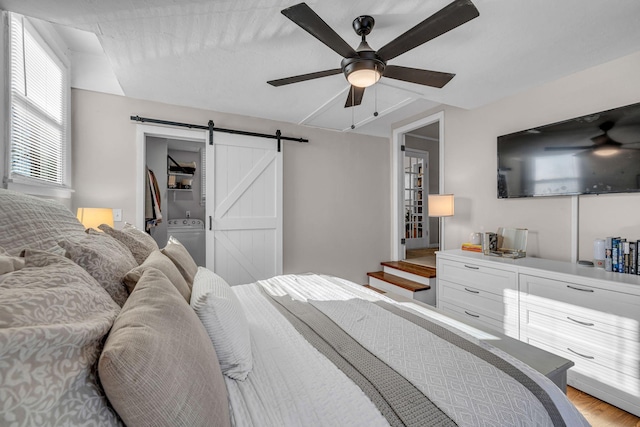 bedroom featuring washer / dryer, a barn door, a ceiling fan, a spacious closet, and a closet