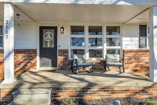 entrance to property with brick siding and a porch