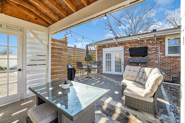 view of patio with french doors, outdoor dining space, and fence