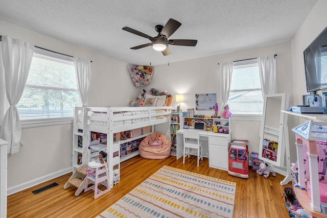 bedroom featuring light wood-type flooring, visible vents, a textured ceiling, and multiple windows