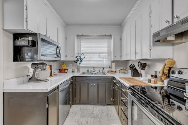 kitchen with light countertops, appliances with stainless steel finishes, a sink, and under cabinet range hood